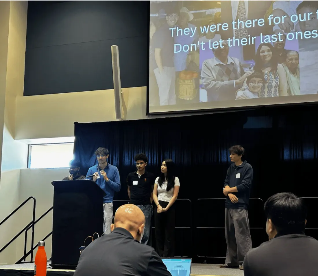 The Nested team on stage presenting, in front of a slide about elder care